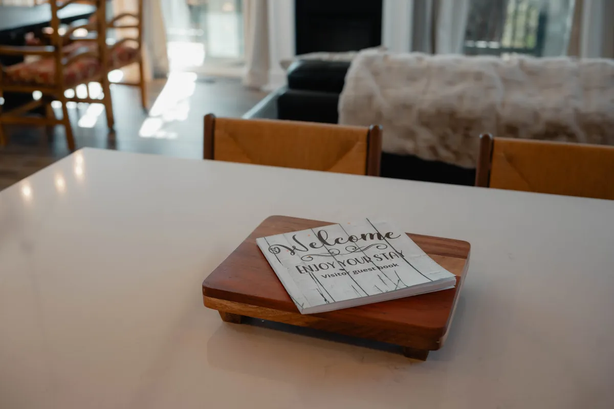 A welcoming dining area with a wooden serving tray, a welcome book, and a table—inviting guests to gather, plan adventures, and enjoy shared meals. The overall mood is warm and inviting, suggesting a perfect spot for coffee at sunrise or a friendly chat before exploring the neighborhood.